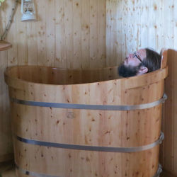Marco in der Holzbadewanne im Tiny House